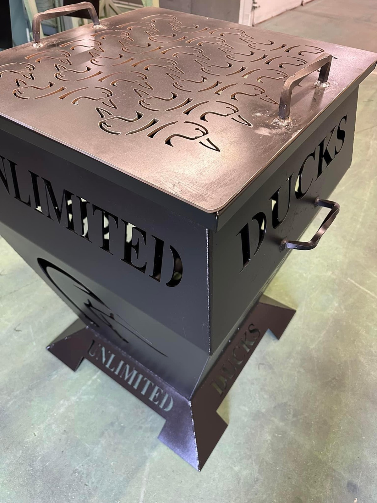 Ducks Unlimited fire pit with a patterned removable lid and handles.