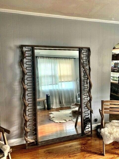 A tall mirror framed with formed metal details.