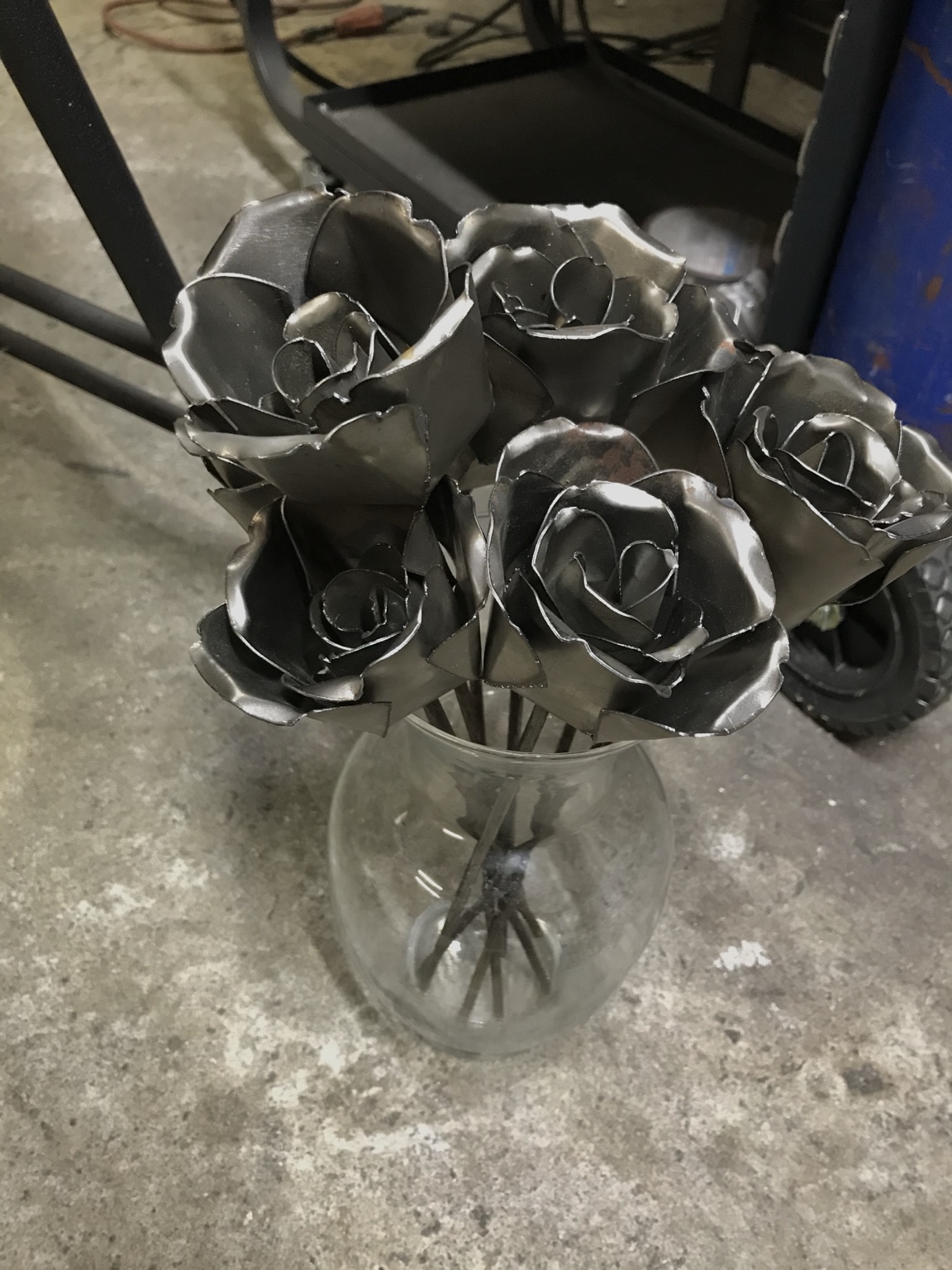 Formed metal roses arranged together in a vase.