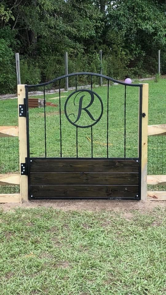 A decorative gate with a circular R monogram and wood lower panel.